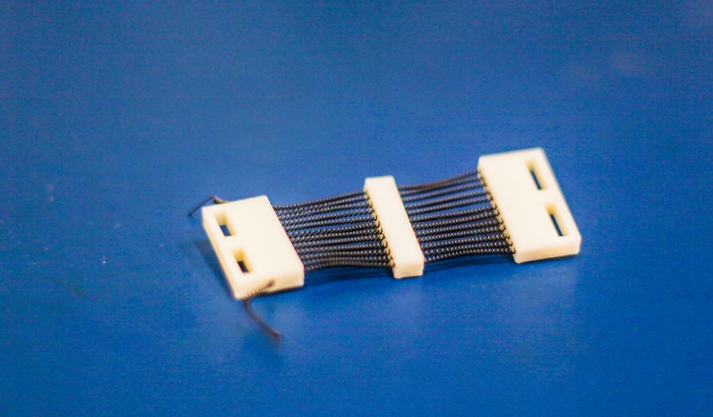 Un dettaglio della cartuccia stampata in 3-D in lega a memoria di forma (SMA) che racchiude 24 attuatori SMA in una struttura di 2.54 cm di larghezza, progettato specificamente per indumenti di compressione attivi.